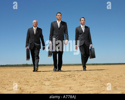 Trois hommes d'affaires avec porte-documents marche à travers désert, pleine longueur Banque D'Images