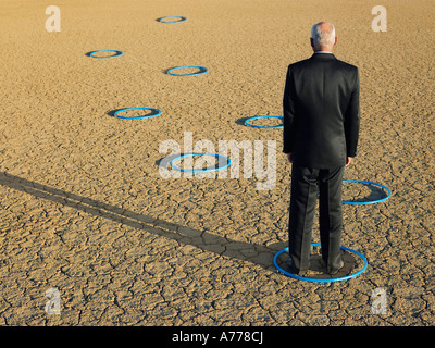 Businessman standing in hoops en désert, vue arrière, pleine longueur Banque D'Images