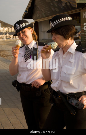 Deux femmes agents de police de manger des glaces à Aberystwyth Ceredigion Pays de Galles UK un soir d'été Banque D'Images