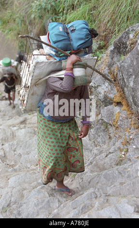 Femme népalaise transportant des marchandises à vendre en haute montagne dans la région de l'Annapurna lieux rencontre près de Jagat Népal village Banque D'Images