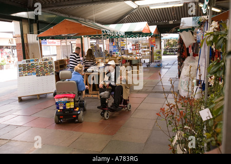 Northwich Cheshire UK Royal Vale Indoor Market Hall l'homme et de la femme dans la mobilité des buggies chatting Banque D'Images