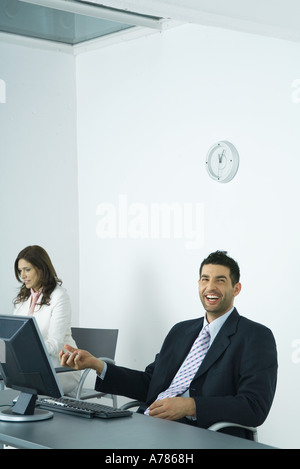 Businessman sitting at desk, holding Yin Yang balls Banque D'Images