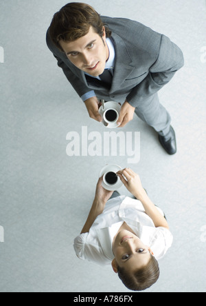 Les associés détenant de tasses de café, à la caméra, jusqu'à pleine longueur, high angle view Banque D'Images