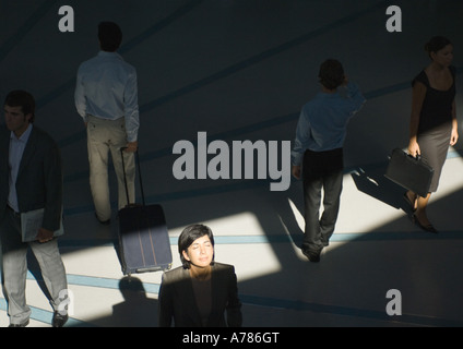 Businesswoman standing avec les yeux fermé en rayon de soleil tandis que les gens passer Banque D'Images