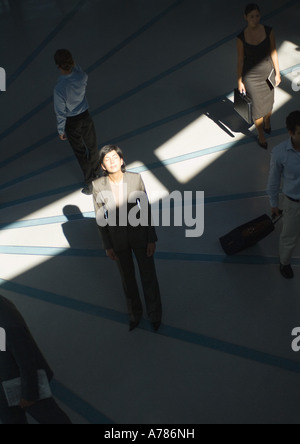 Businesswoman standing avec les yeux fermé en rayon de soleil tandis que les gens passer Banque D'Images