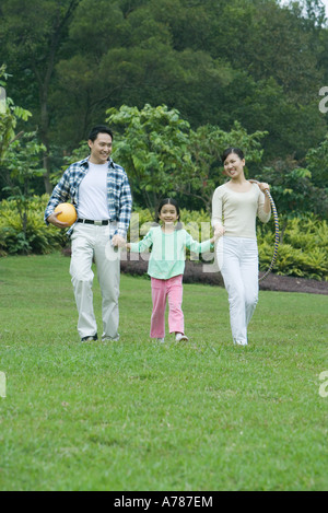 Fille qui marche dans l'herbe avec les parents Banque D'Images