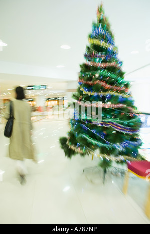 Femme shopper walking passé Christmas Tree in mall Banque D'Images