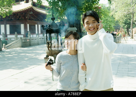 Couple en train de marcher près de temple, man using cell phone and woman holding camera Banque D'Images