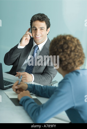 D'affaires et un jeune homme habillé en passant, man using cell phone Banque D'Images