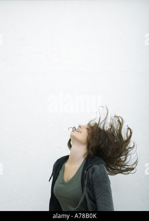 Young woman flipping cheveux en arrière, fond blanc Banque D'Images