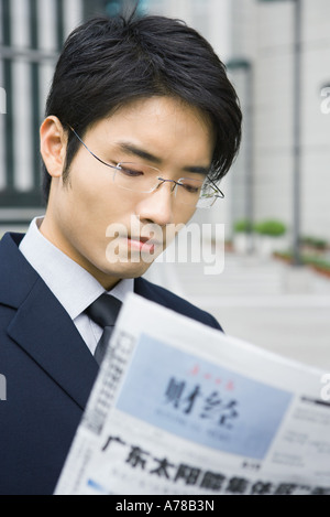 Businessman reading journal chinois Banque D'Images