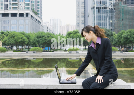 Businesswoman using laptop par l'eau dans office park Banque D'Images