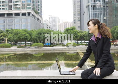 Businesswoman using laptop par l'eau dans office park Banque D'Images