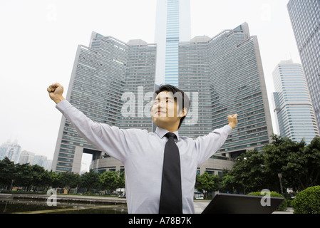 Businessman standing with arms out, gratte-ciel en arrière-plan, low angle view Banque D'Images