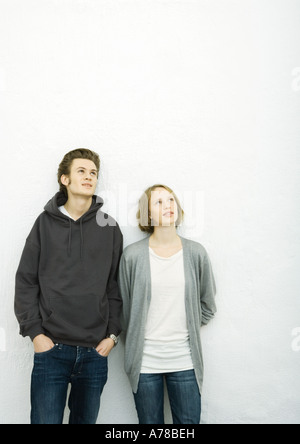 Jeune couple leaning against wall, looking up Banque D'Images