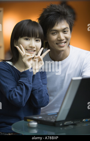 Jeune couple, woman making 'v' signe avec les doigts Banque D'Images