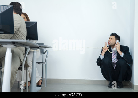 Woman holding coin, téléphone, à la recherche de collègues et doigt de maintien à l'avant des lèvres Banque D'Images
