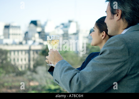 Partenaires d'affaires holding up verres de champagne, skyline en arrière-plan Banque D'Images