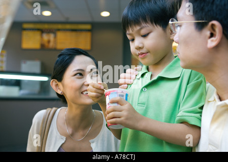 Boy eating snack sucré, parents Banque D'Images