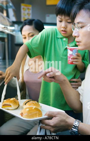 Family eating fast food, boy picking up bun à partir du bac Banque D'Images