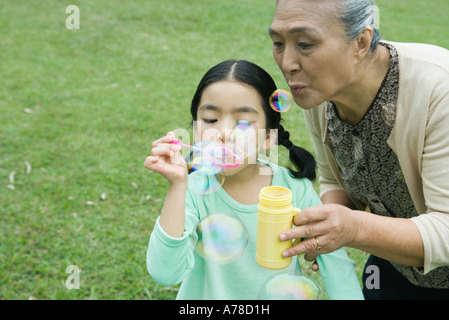 Petite fille et sa grand-mère blowing bubbles Banque D'Images