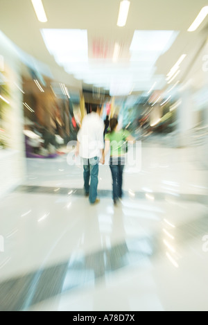 Couple en train de marcher dans un centre commercial, vue arrière, blurred motion Banque D'Images