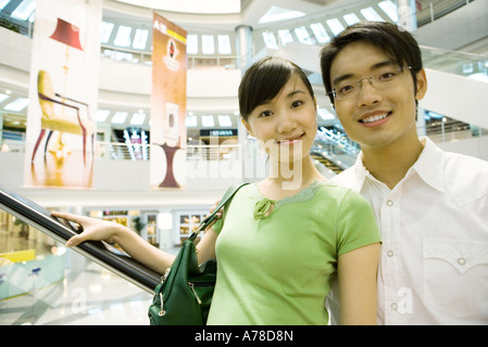 Dans l'escalator couple shopping mall, smiling at camera Banque D'Images