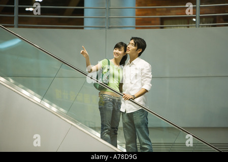 Dans l'escalator couple shopping mall, woman pointing out du châssis Banque D'Images