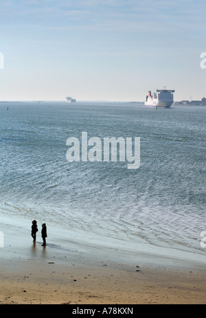Un couple sur une plage de sable fin et d'expédier dans les écrans de la distance sur l'estuaire de la Rivière Gota Suède Göteborg Banque D'Images