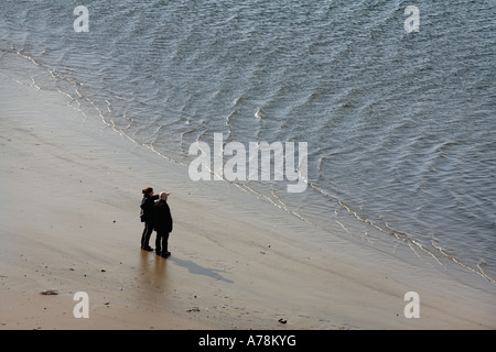 Un couple sur une plage de sable fin à la recherche sur l'eau Banque D'Images