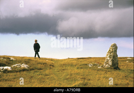 Femme marchant loin de la tempête sur un paysage ancien sombre au-dessus de Llandudno Wales Royaume-Uni Banque D'Images