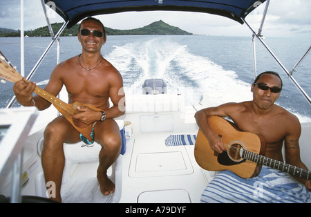Deux hommes de l'endroit sur la vitesse bateau Bora Bora jouant la musique traditionnelle du Pacifique Sud Banque D'Images
