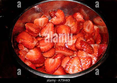 Un bol en acier inoxydable de fraises rouge sur fond sombre Banque D'Images