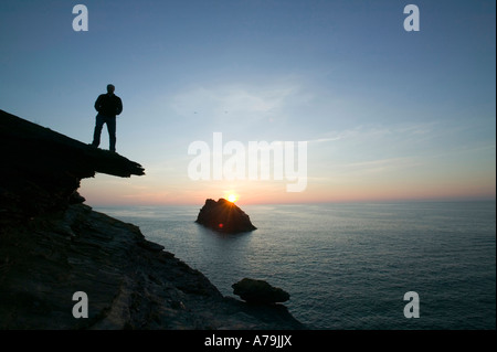 Un homme sur la falaise surplombant l'île de Meachard au coucher du soleil de Boscastle, Cornwall, UK Banque D'Images