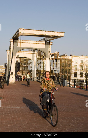 Biker blanc passage pont Magere Brug Skinny ou sur la rivière Amstel, Amsterdam Pays-Bas Banque D'Images