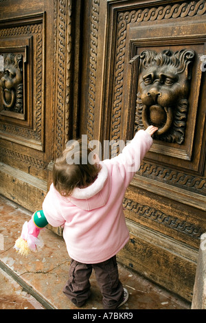 Est-ce que quelqu'In. Jeune fille essayant d'ouvrir une porte sculptée, Prague Banque D'Images