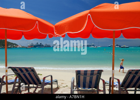 Plage Rouge parasols et chaises longues sur la plage à Grand Bay Philipsburg avec boy walking in surf Saint Martin île des Caraïbes Banque D'Images