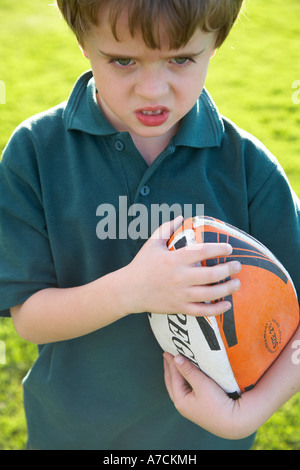 Garçon avec ballon de rugby à la dur Banque D'Images