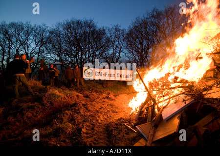 Protester contre les cultures génétiquement modifiées GM bannières Dorset foule gens champ balise anti incendie agriculture arbres crépuscule flammes brûler c Banque D'Images