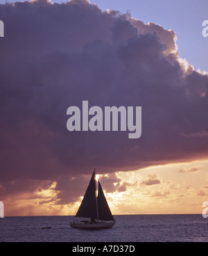 Petit yacht voile au coucher du soleil dans la mer des Caraïbes Banque D'Images