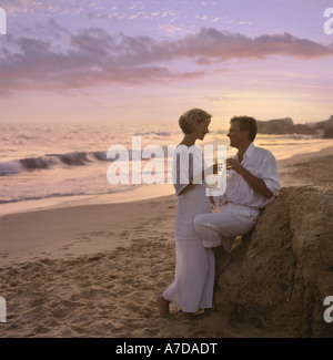 Couple, vêtu de blanc, sur la plage au crépuscule Banque D'Images