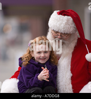 Petite fille assise sur les genoux du Père Noël au café en plein air Banque D'Images