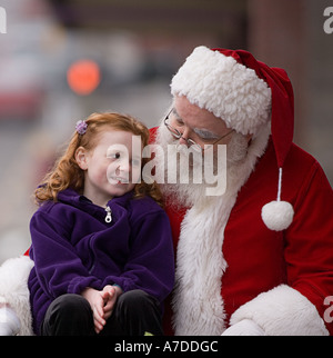 Petite fille assise sur les genoux du Père Noël au café en plein air Banque D'Images