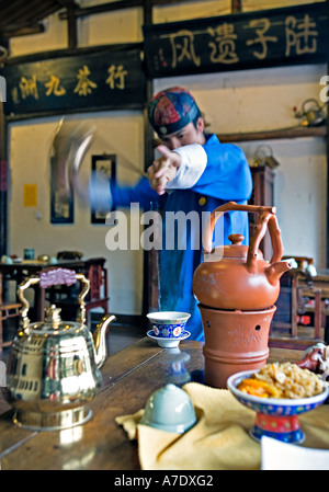 HANGZHOU, Chine thé thé jeune serveur verse de derrière son dos à l'aide d'un bec long teapot Banque D'Images