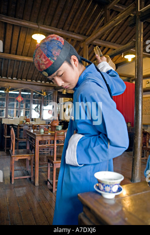 HANGZHOU, Chine thé thé jeune serveur verse de derrière son dos à l'aide d'un bec long teapot Banque D'Images