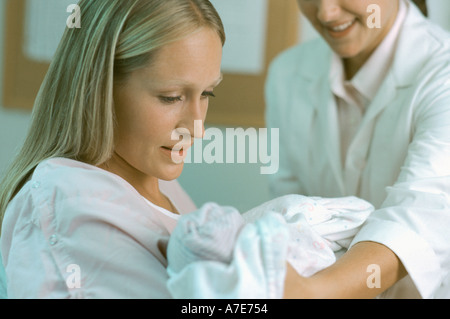 Nouveau né de mère recevant nurse in hospital room Banque D'Images