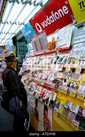 Nov 09, 2004 - Le client à la recherche de téléphones mobiles à l'extérieur d'un magasin à Akihabara Electric Town () dans la capitale japonaise de Tokyo. Banque D'Images