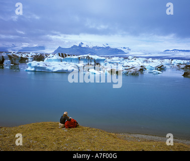 Un couple jouit de la vue sur le lac et le glacier glacier Vatnajoekull Breitharlon, Islande Banque D'Images