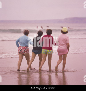 Groupe de quatre dames âgées vêtus de shorts à marcher le long du bras de mer sur la plage de Newquay Cornwall England Banque D'Images