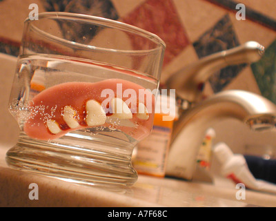 Les fausses dents trempez dans salle de bains verre Banque D'Images